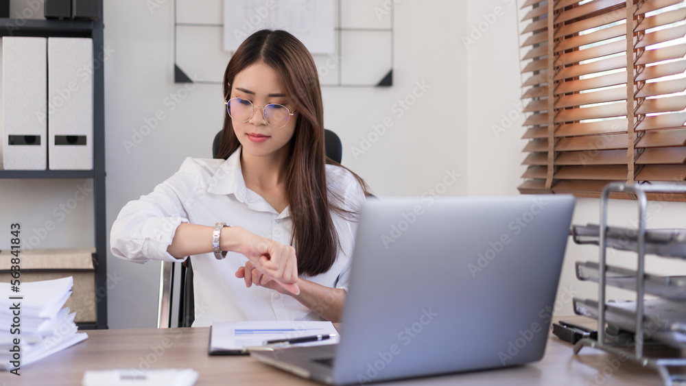 Business concept, Businesswoman is look at the time on the wristwatch after working hard in office