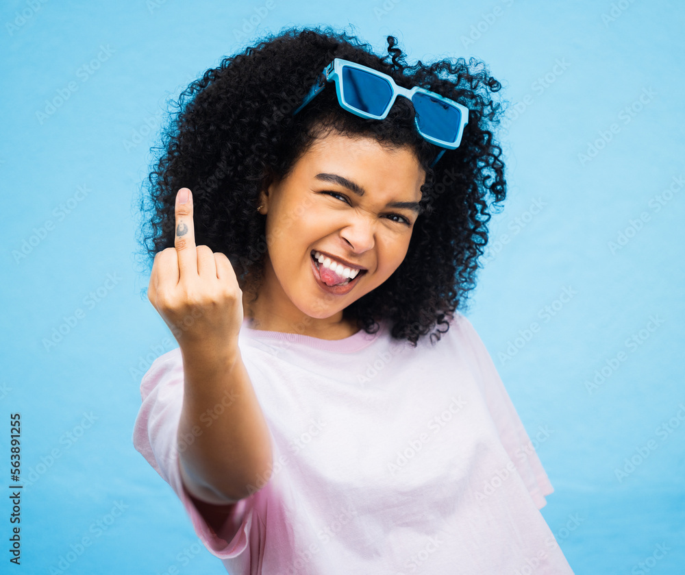 Portrait, middle finger and hand, emoji and black woman in studio, rude and carefree on a blue backg