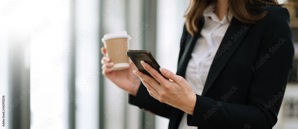 woman using laptop and typing on laptop and holding coffee cup in cafe, home office in morning light