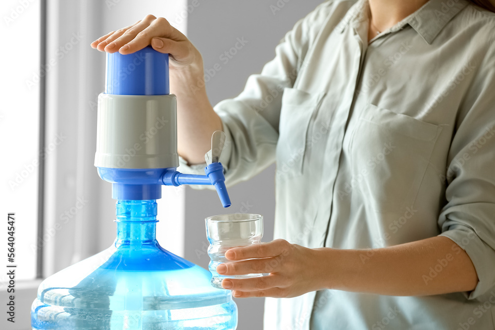 Woman pouring clean water from bottle into glass at home