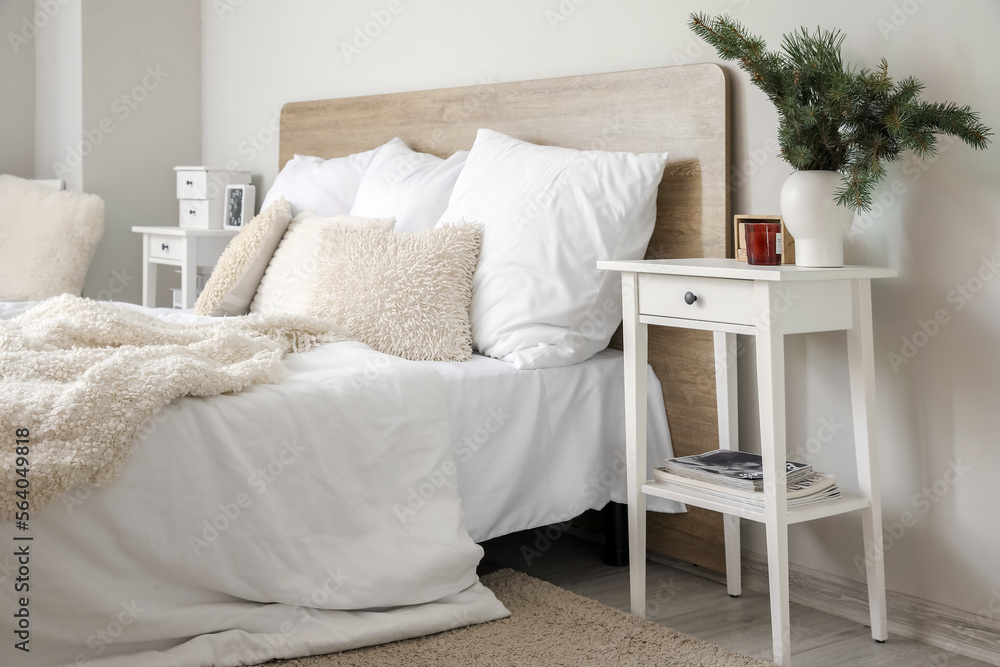 Vase with fir branches, candle and cube calendar on bedside table in room