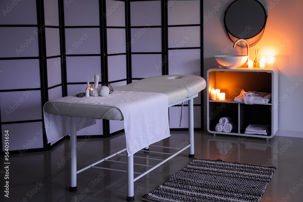 Interior of dark spa salon with couch, sink and folding screen