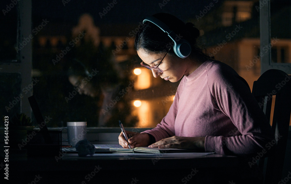 Headphones, writing and student studying at night for a test, exam or college assignment. University