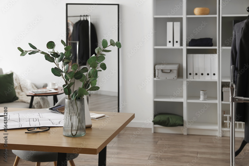 Vase with eucalyptus on tailors table in atelier