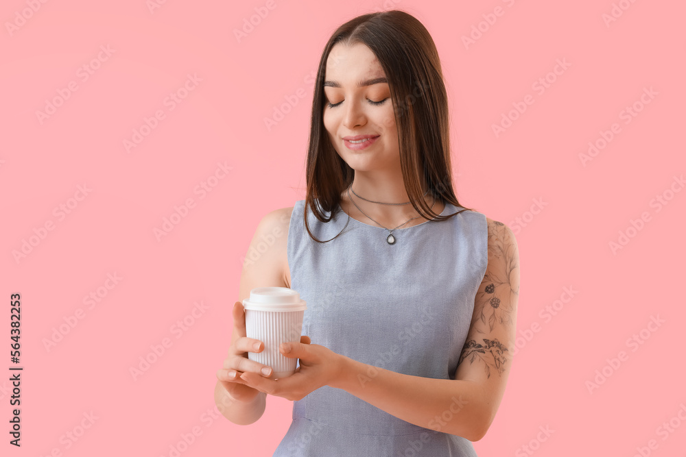 Young woman with takeaway cup of coffee on pink background