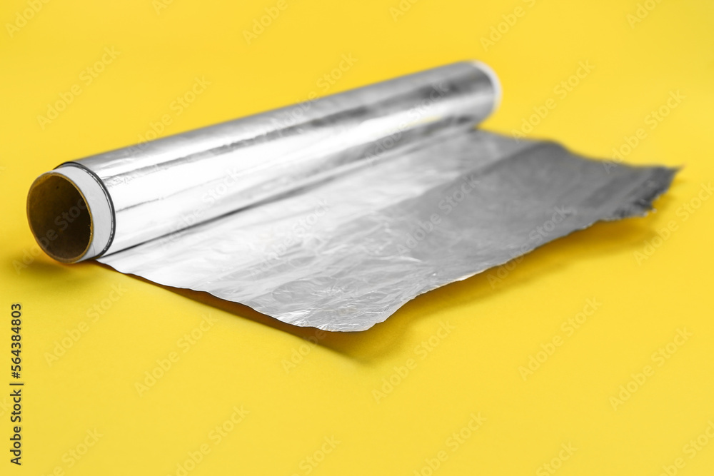 Roll of aluminium foil on yellow background