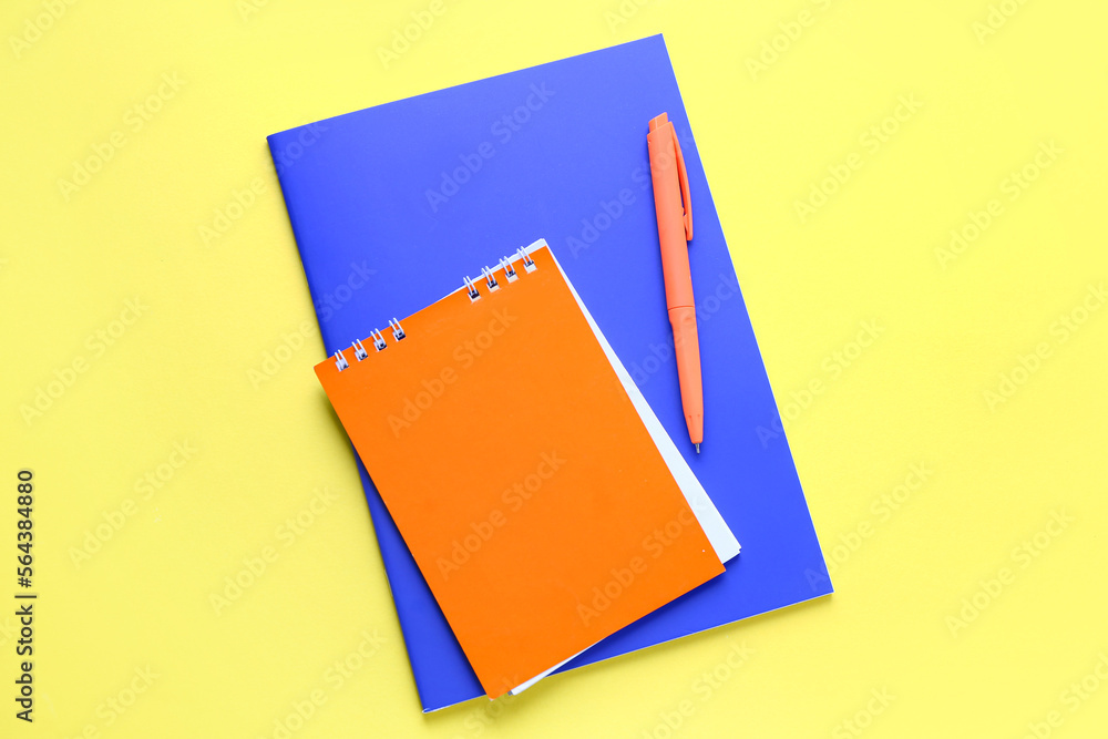 Notebooks with pen on yellow background