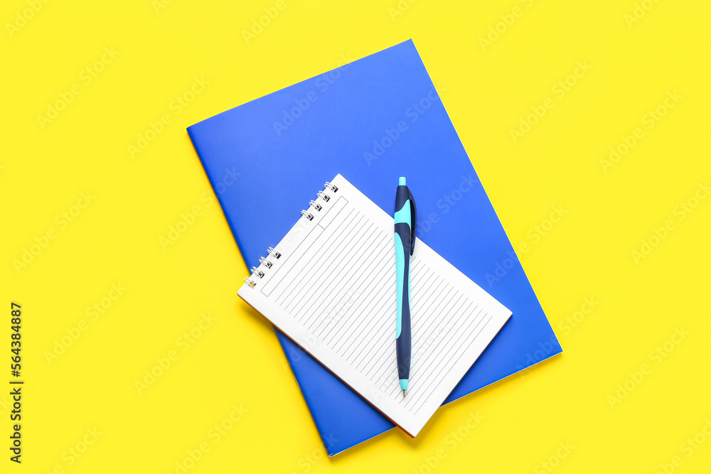 Notebooks with pen on yellow background