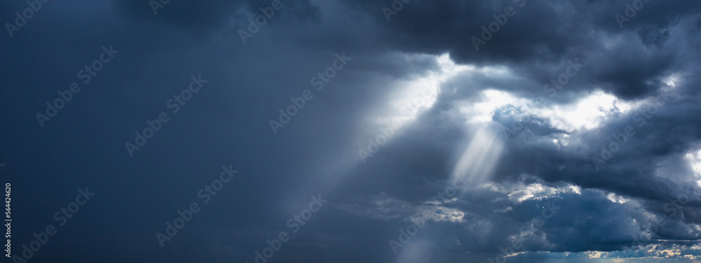 Storm clouds and rays of the sun on a dark background.