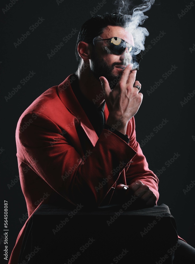 Fashion, smoking and red with a man model in studio on a dark background wearing a suit for style. S