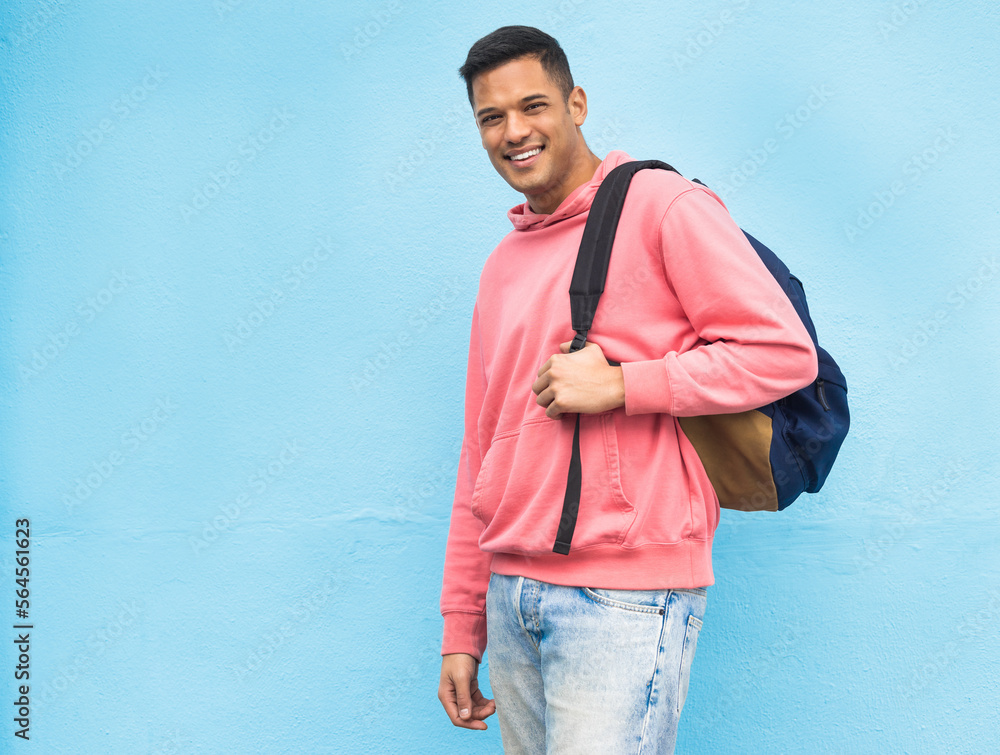 Portrait, university and man student with backpack in studio, happy and smile on blue background. Fa