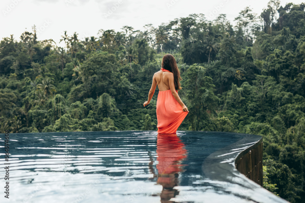 Female standing in swimming pool at luxury resort