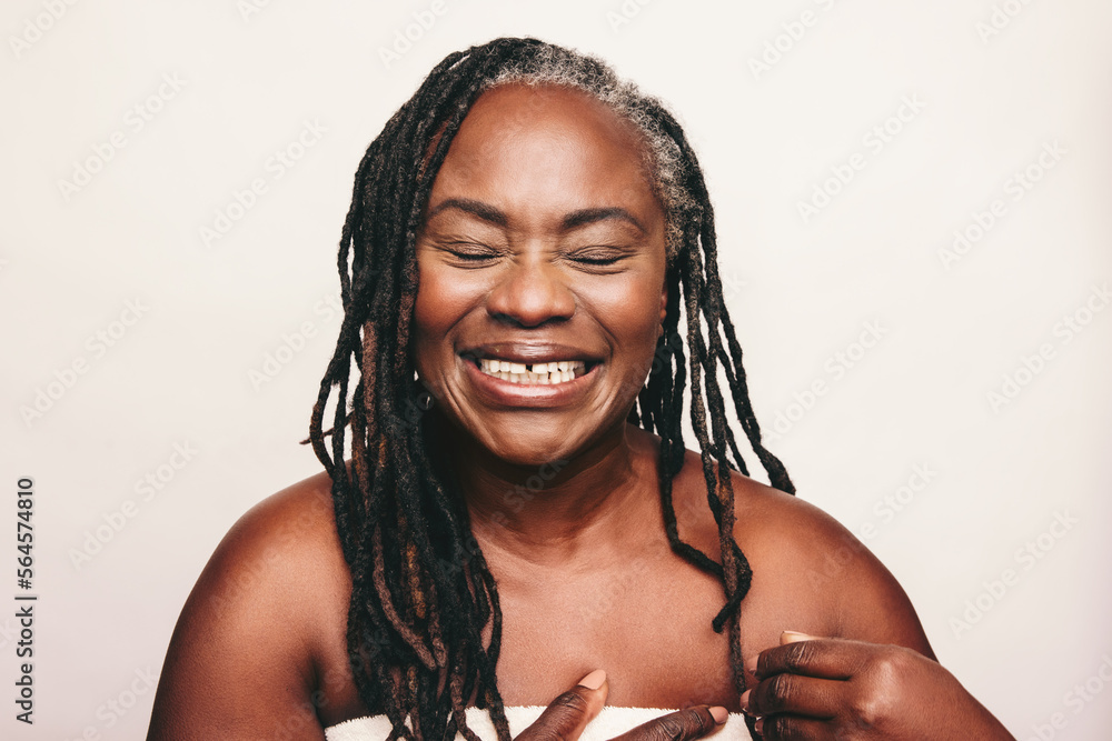 Cheerful mature woman laughing cheerfully in a bath towel