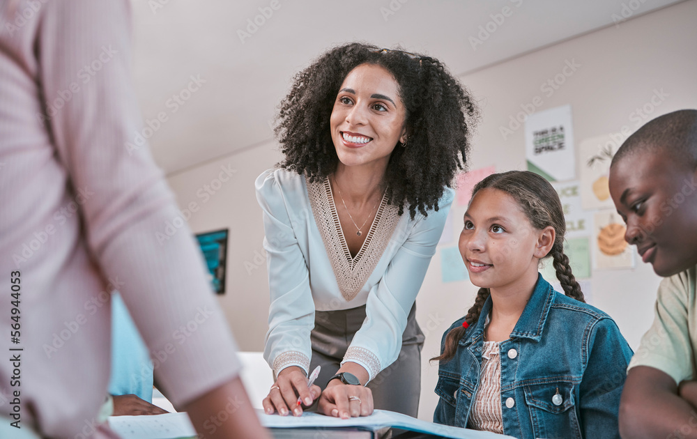 Happy teacher in classroom with children, helping students with homework and writing in book. Educat