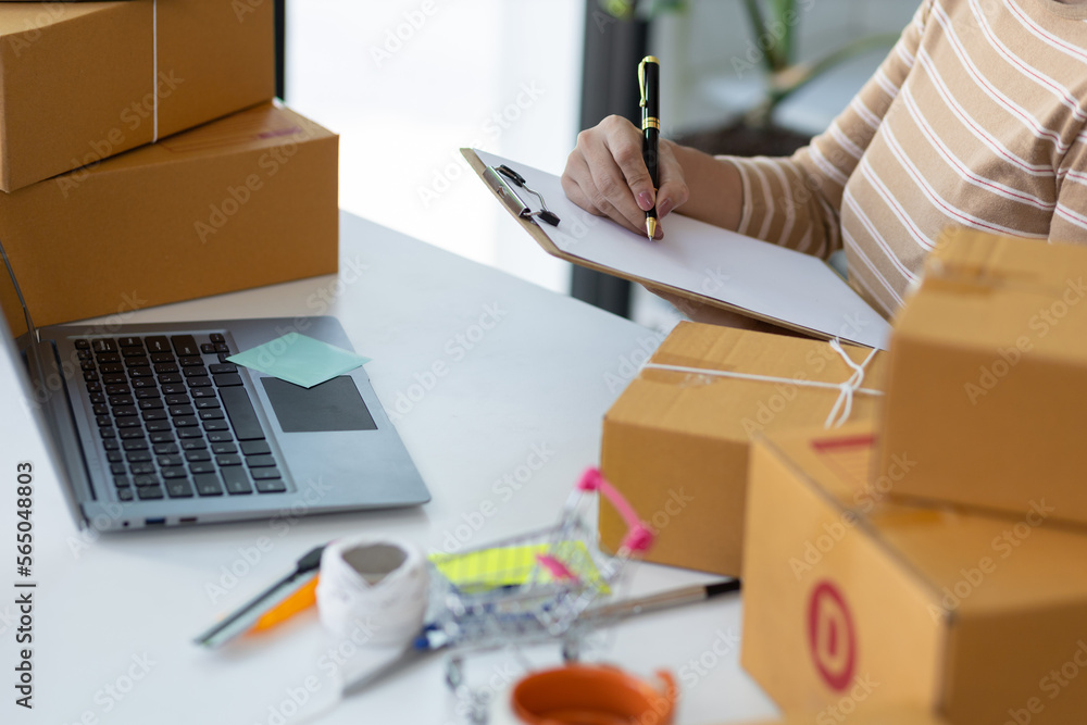 Woman starting a small business in a home office is working on a laptop to check orders from the int