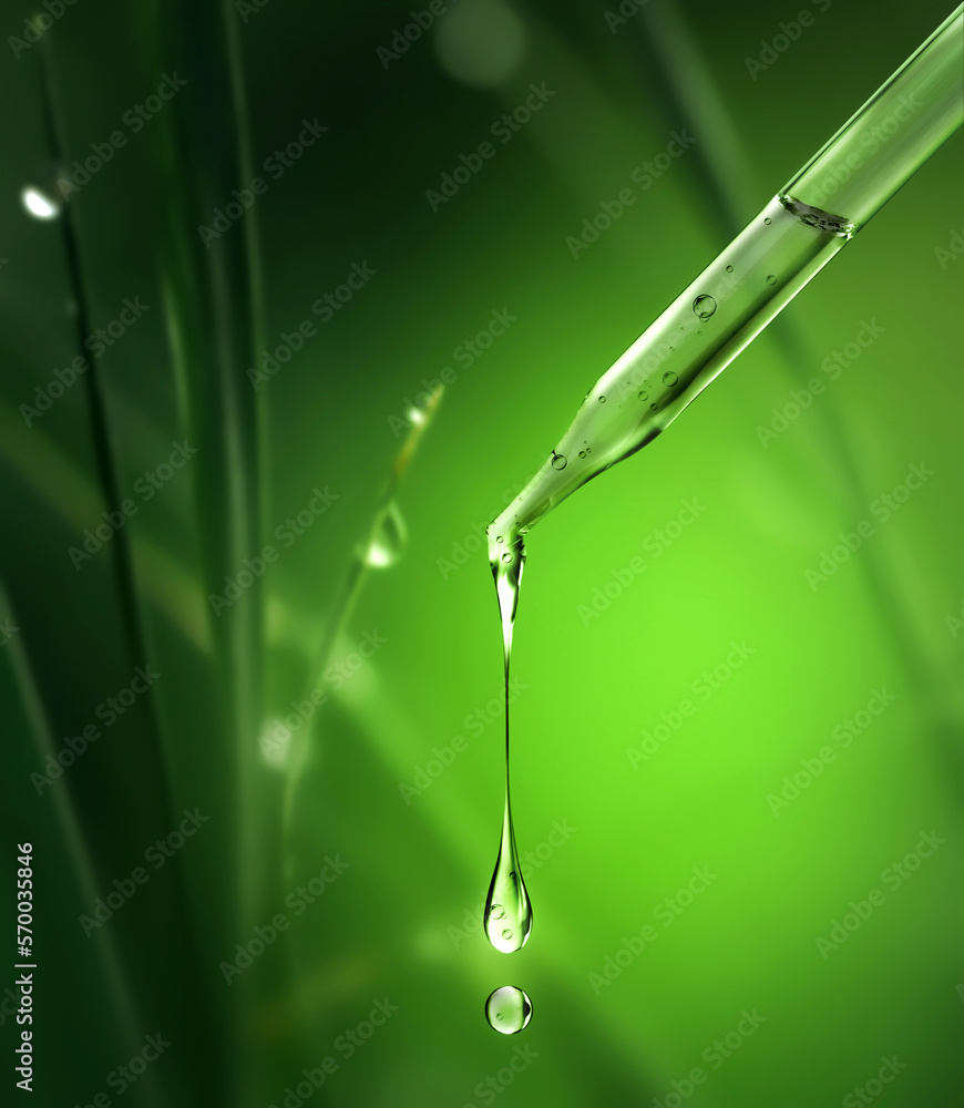 Cosmetic pipette with falling drops close-up on a natural blurred background