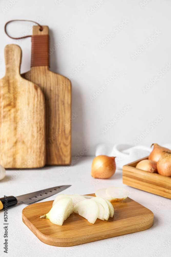 Wooden board with cut onion on light background