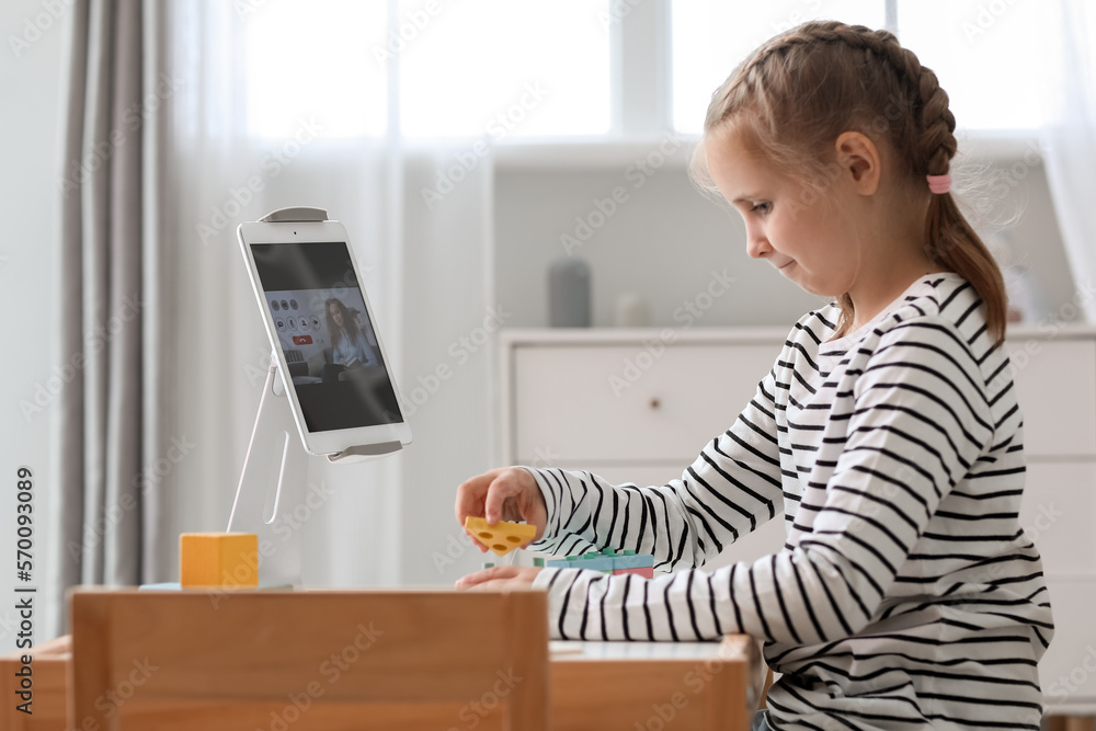 Upset little girl with cubes having online psychologist session at home