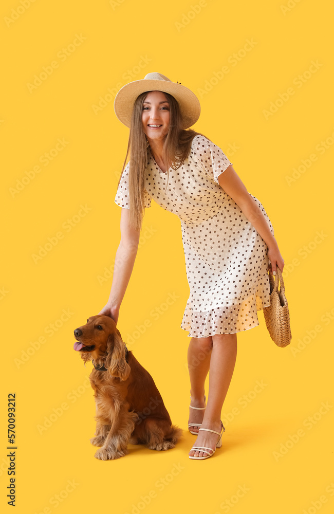 Young woman with red cocker spaniel on yellow background