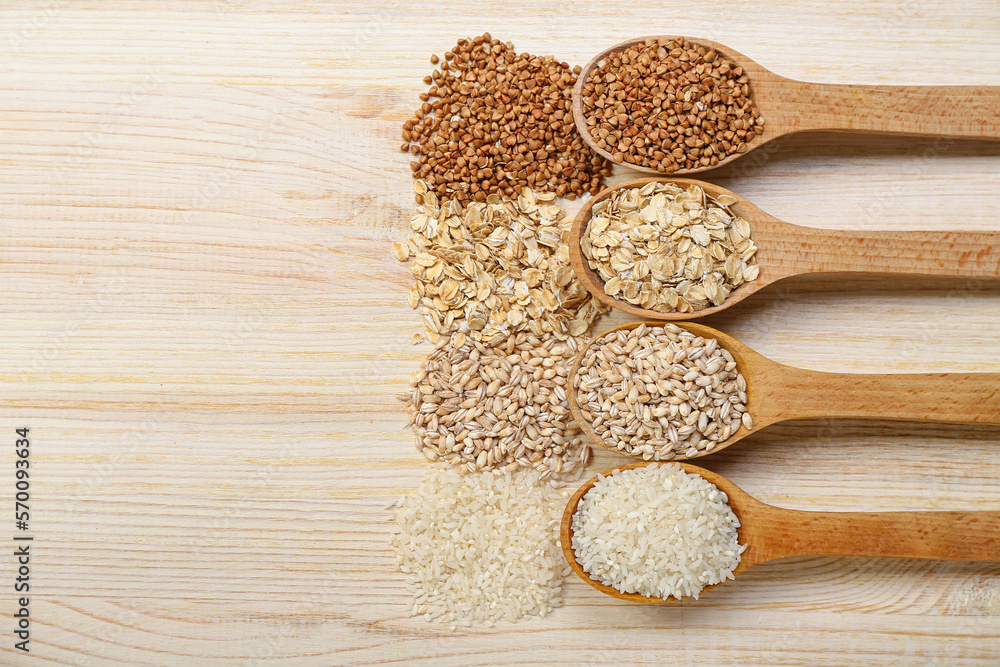 Spoons with different cereals on wooden background