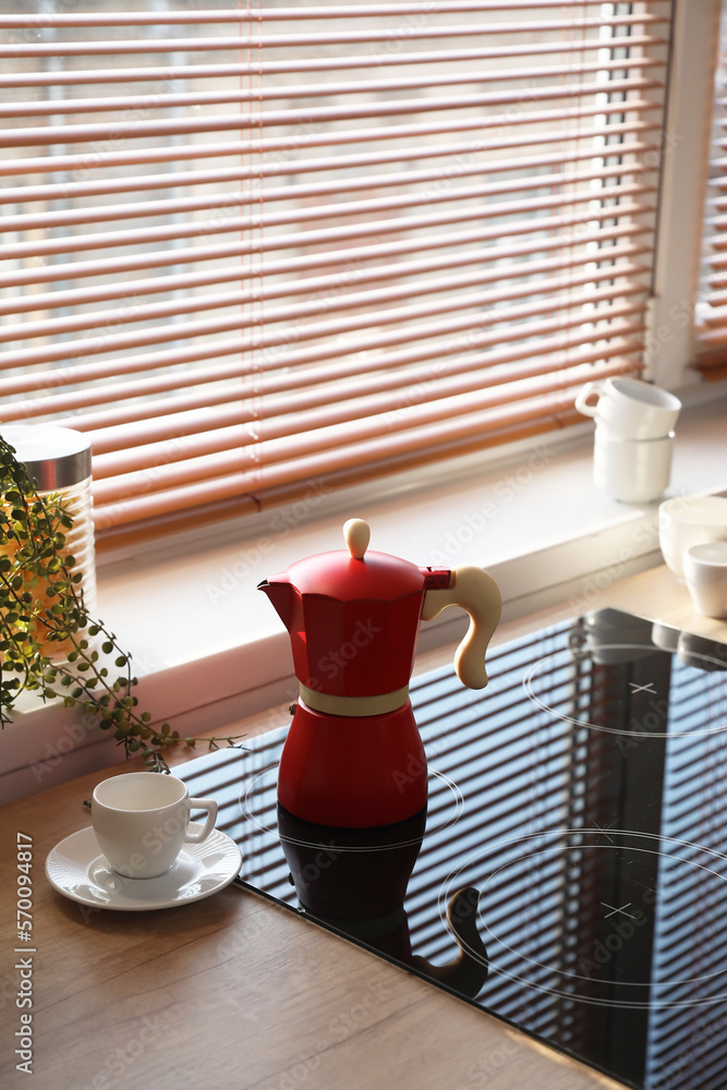 Geyser coffee maker on electric stove in kitchen near window