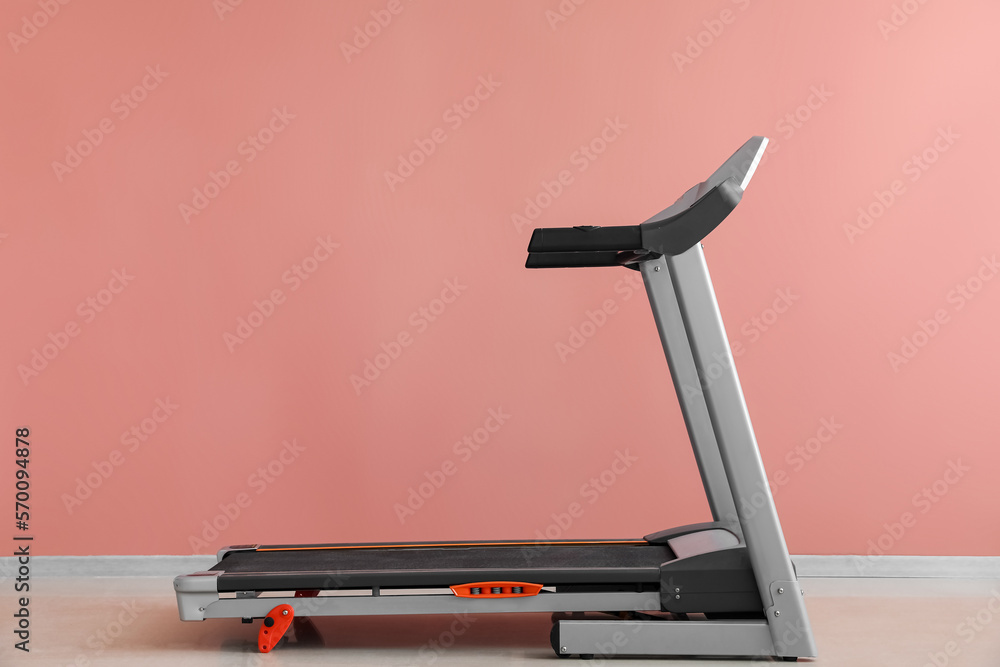 Interior of room with modern treadmill near pink wall