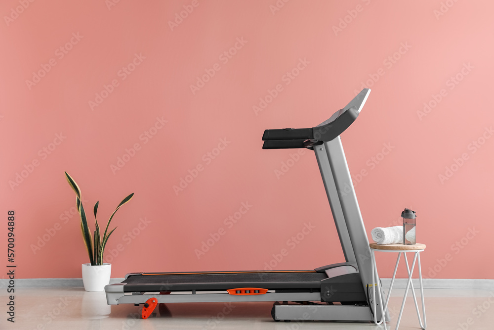 Interior of room with modern treadmill near pink wall