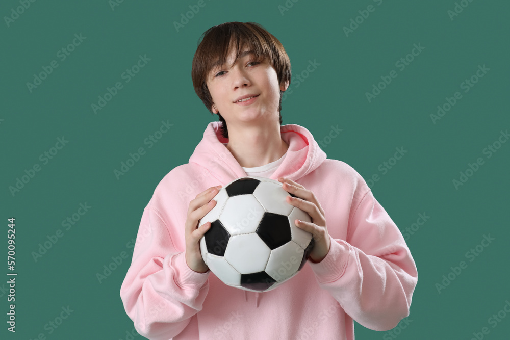 Teenage boy with soccer ball on green background