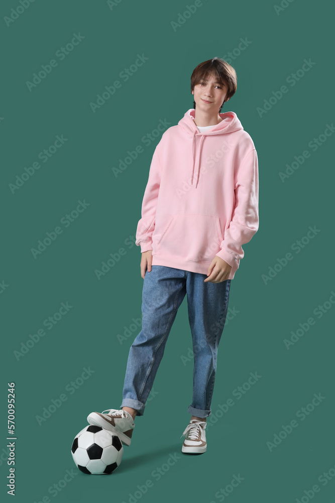 Teenage boy with soccer ball on green background