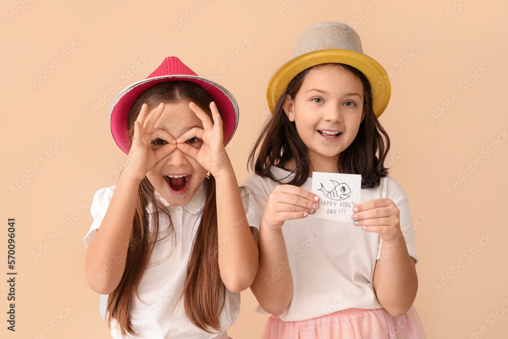 Little girls and sticky paper with text HAPPY FOOLS DAY on beige background