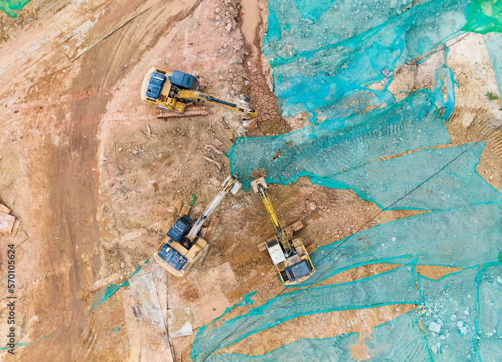 Excavator on earthmoving at construction site, aerial view.