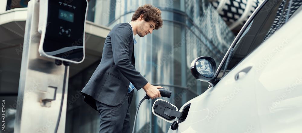 Below view closeup image of progressive black suit businessman recharge battery of his electric vehi