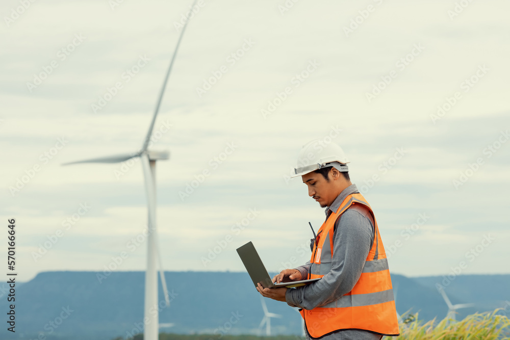 Engineer working on a wind farm atop a hill or mountain in the rural. Progressive ideal for the futu