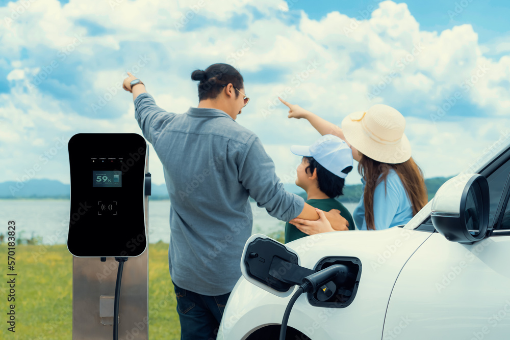 Concept of progressive happy family with electric vehicle enjoy their time at natural outdoor scenic