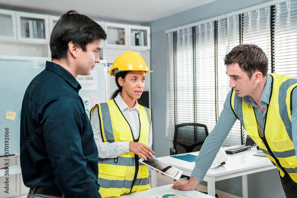 Engineers and competent employer discussing plans and blueprints together with tablet in the office.