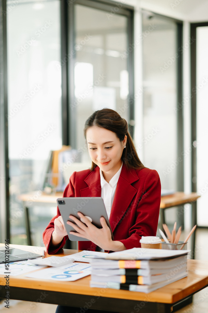 Young beautiful woman using laptop and tablet while sitting at her working place. Concentrated at wo