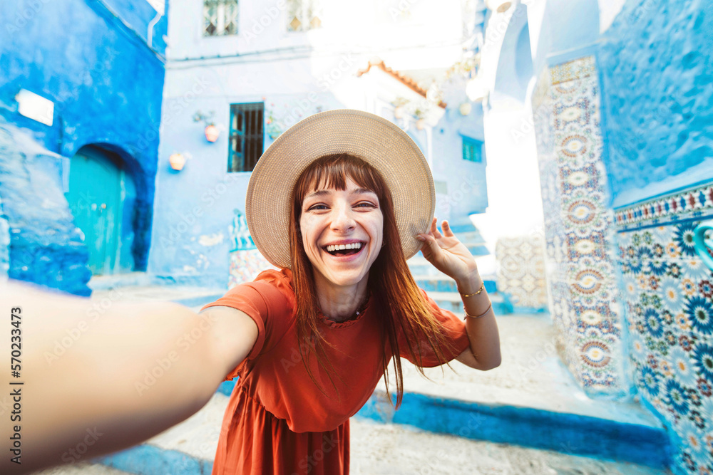 Young woman with red dress visiting the blue city Chefchaouen, Marocco - Happy tourist walking in Mo