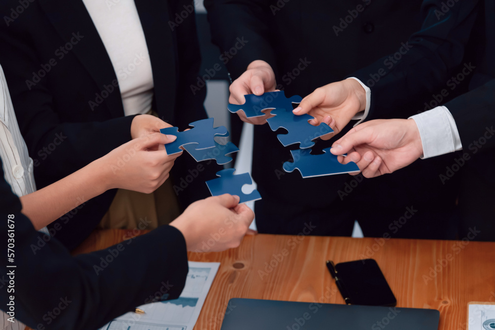 Closeup top view business team of office worker putting jigsaw puzzle together over table filled wit