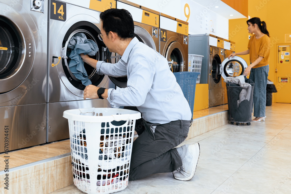 Asian people using qualified coin operated laundry machine in the public room to wash their cloths. 