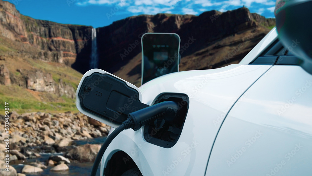 Electric car charging energy from charging station in the natural scenery, waterfall and stream back