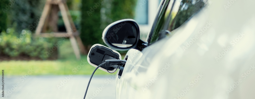 Closeup electric vehicle plugged-in with cable from charging point powered for progressive concept b