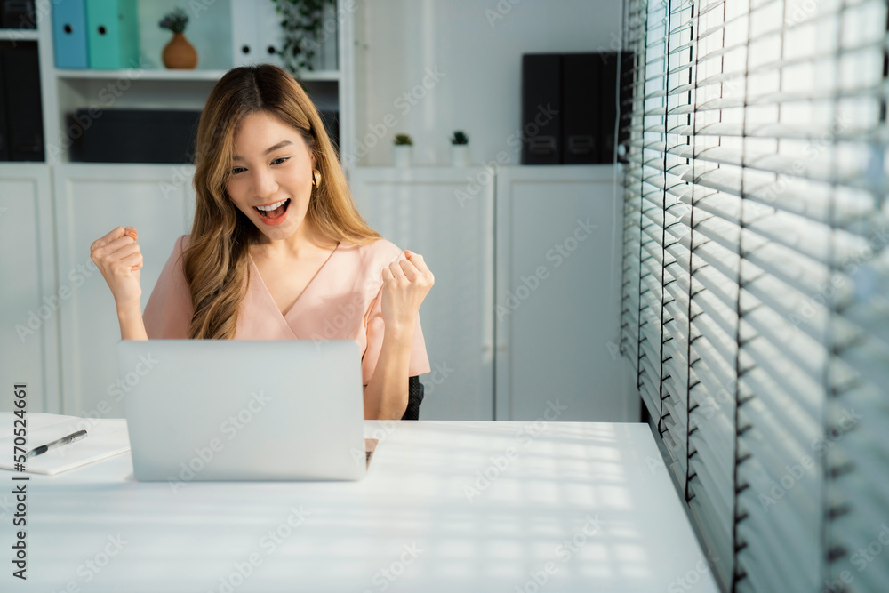 A young female employee receives a promotion, good news or finished her task and overjoyed for being