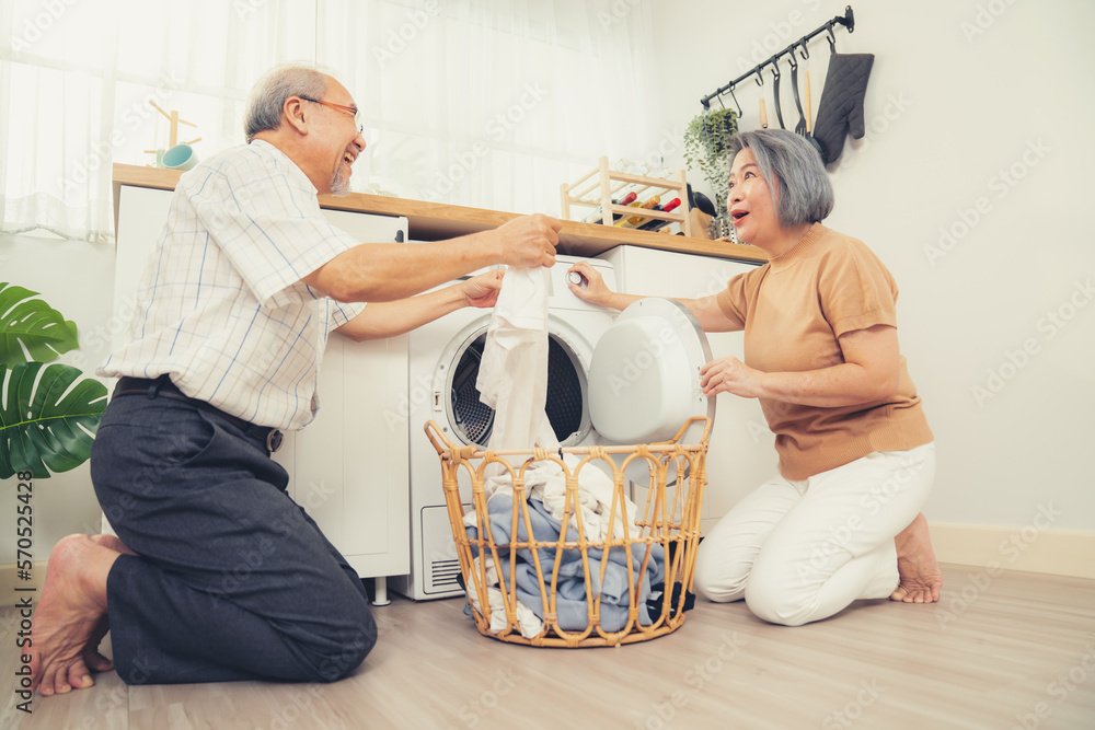 Senior couple working together to complete their household chores at the washing machine in a happy 