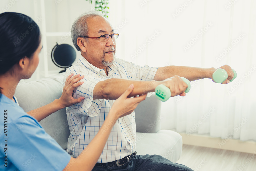 Contented senior patient doing physical therapy with the help of his caregiver. Senior physical ther