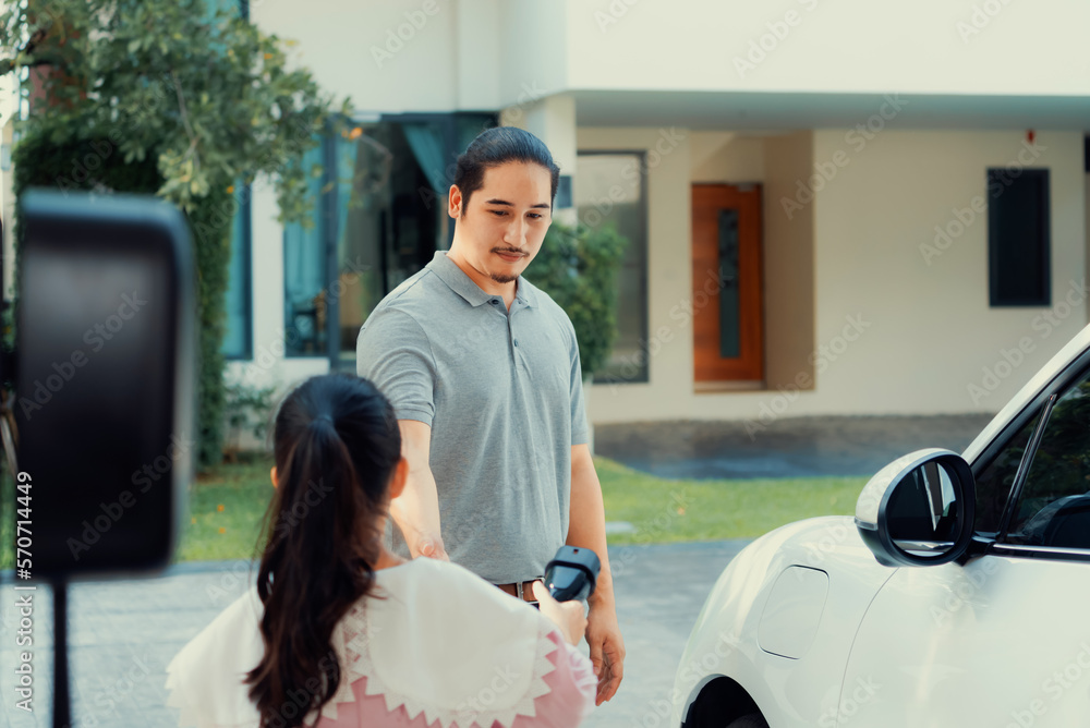 Progressive father and daughter returned from school in electric vehicle that is being charged at ho