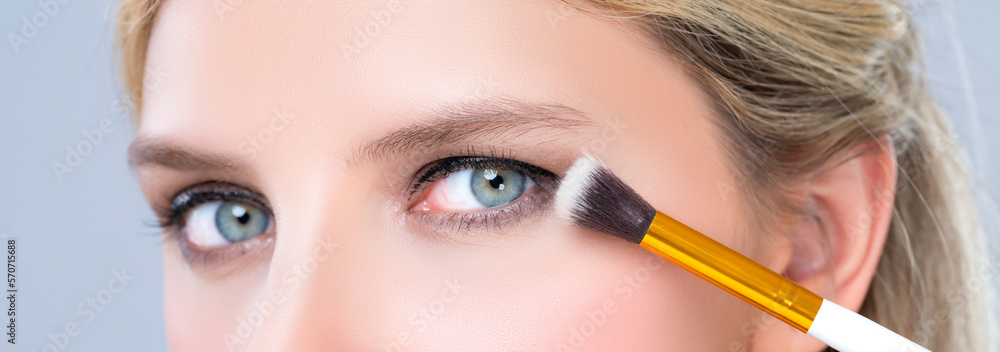 Closeup beautiful girl with flawless applying alluring eye shadow makeup with eyeliner brush. Cosmet