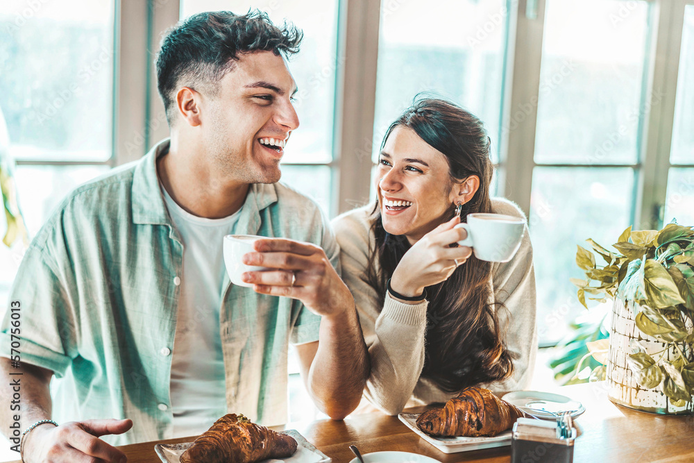 Happy couple enjoying breakfast drinking coffee at bar cafeteria - Lifestyle concept with guy and gi