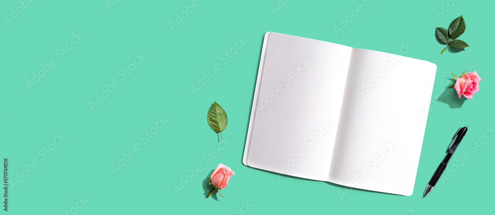 Open notebook or diary with a pen from above with rose buds- flat lay