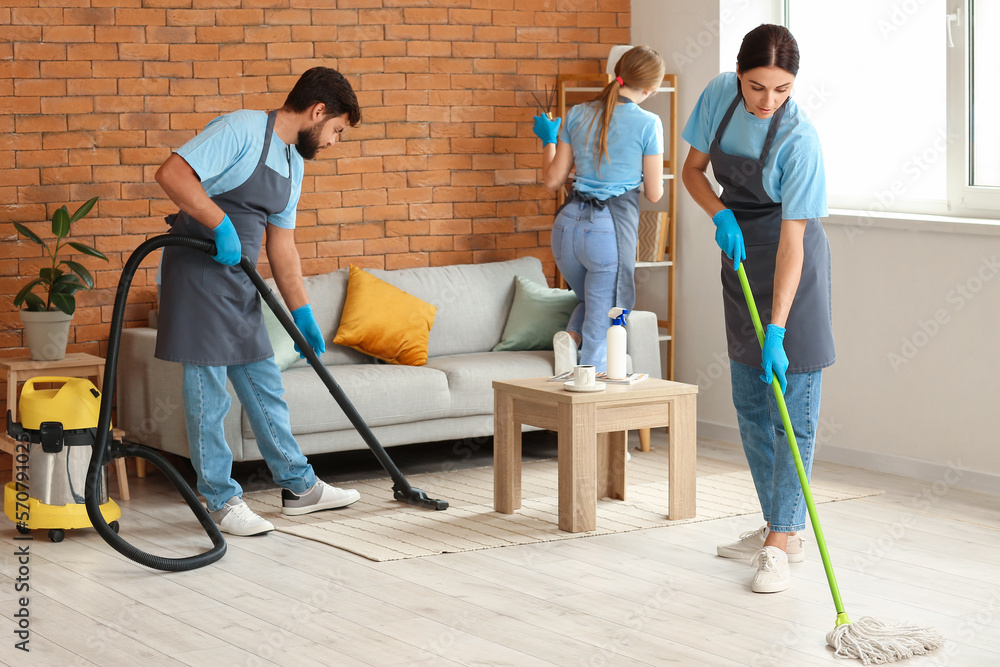 Young janitors cleaning in living room