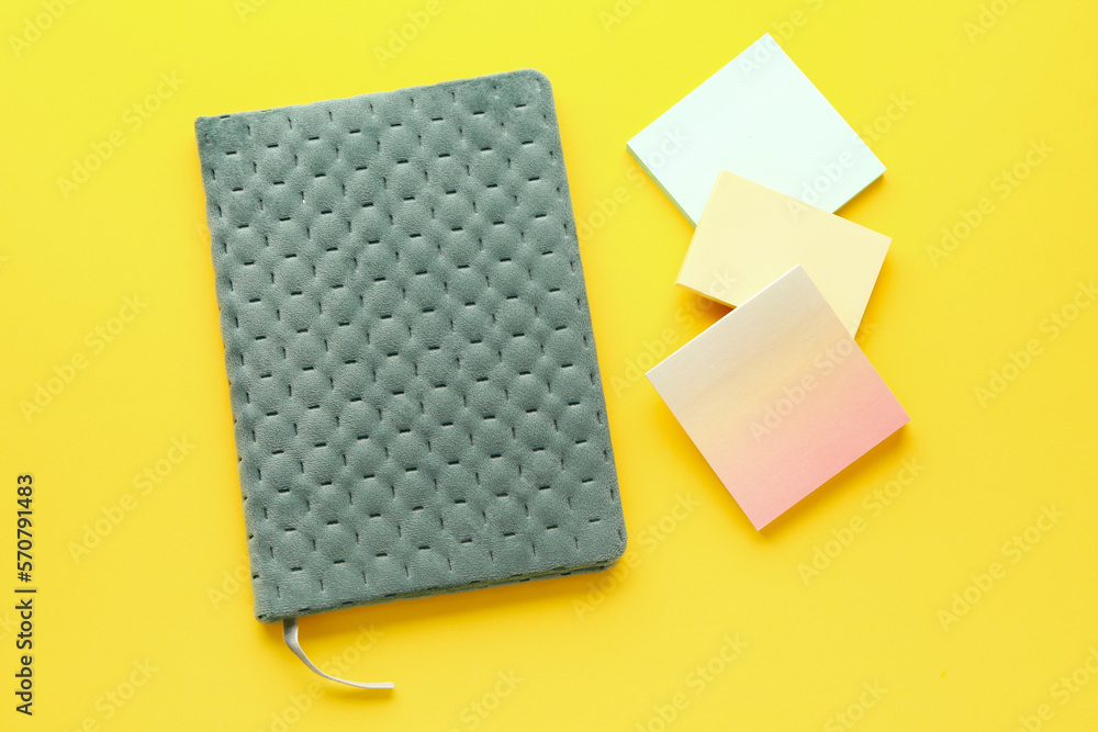 Notebook and sticky notes on yellow background